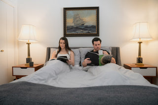 A couple reading on the queen size bed in the master bedroom, showcasing the peaceful ambiance of Cellar House.