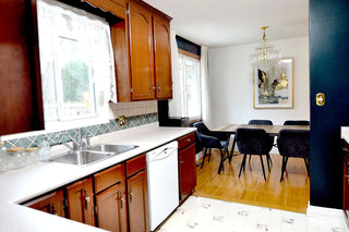 Discover The Chef's Haven, a stylish kitchen in Cellar House, featuring a sink, window, and a chic dining area with an elegant chandelier.